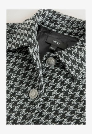 Sivi i crni kaput s kariranim uzorkom, s ovratnikom, metalnim detaljima na dugmadima i glatkom unutarnjom podstavom. Oznaka prikazuje marku "NEXT."