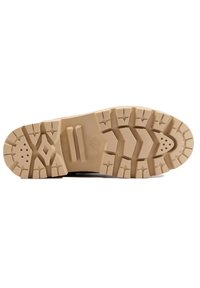 Semelle en caoutchouc marron avec de profondes rainures et de multiples motifs de traction, présentant une couleur beige et une texture lisse avec des trous de drainage.
