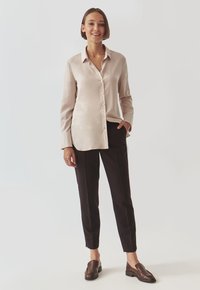 Light beige long-sleeve shirt with a button front, tailored fit, and soft texture, paired with black slim-fit trousers and brown loafers.