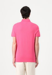 Poloshirt in leuchtendem Pink, aus Baumwollmischung, mit kurzen Ärmeln und umklappbarem Kragen, Rückansicht, die die glatte Textur und Passform betont.