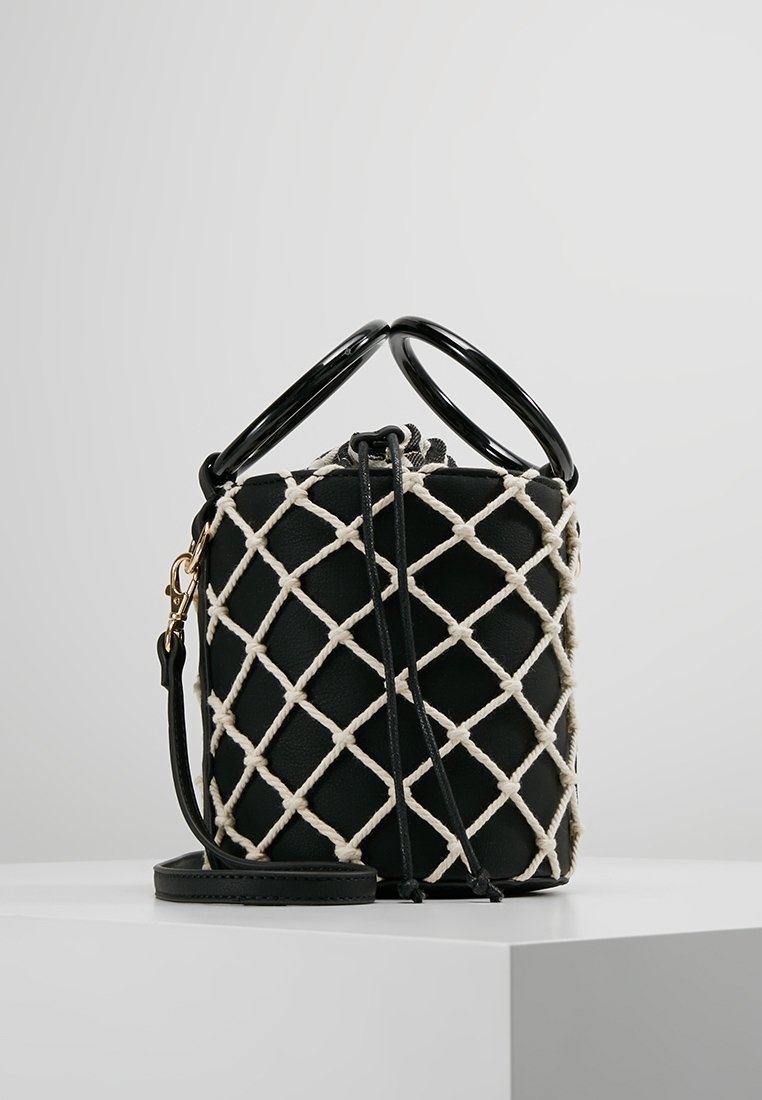 Czarna torebka na ramię z pikowanym wzorem, podkreślającym krzyżujące się paski w kolorze kremowym. Posiada dwa okrągłe czarne uchwyty oraz odpinany pasek.