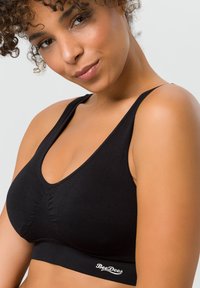 Schwarzer kabelloser Bralette aus weichem Stoff, mit Rundhalsausschnitt, gerafftem Mittelteil und einem Logo-Akzent am Bund.