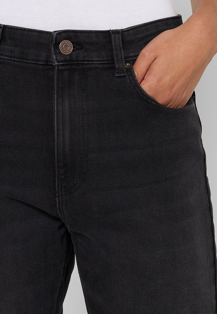 Schwarze Denim-Jeans mit einem taillierten Design, Five-Pocket-Stil und sichtbarem Kupferknopfdetail am Bund.