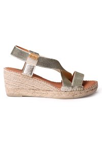 Sandale compensée en métal doré avec une base en jute tressé, dotée de fines lanières croisées. Texture lisse avec un talon robuste et une semelle intérieure en cuir.
