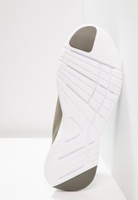 Semelle de chaussure en caoutchouc blanc solide avec des accents gris texturés, présentant un motif géométrique et un design flexible pour une meilleure traction.