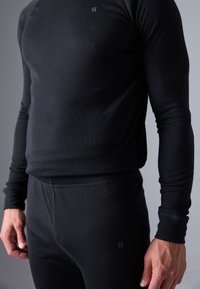 Top negru cu mâneci lungi și pantaloni asortați, confecționați dintr-un material moale și elastic. Design ajustat și detaliu mic cu logo pe top.