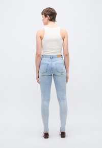 Στενά τζιν σε ανοιχτό μπλε χρώμα με μέση μέσου ύψους, σχεδιασμό με πέντε τσέπες και δερμάτινη ετικέτα στη ζώνη της μέσης στο πίσω μέρος. Ύφασμα απαλό και ελαστικό.