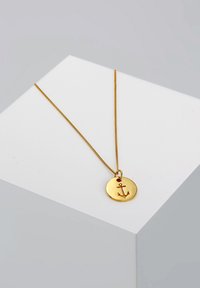 Guldring med en cirkulær vedhæng, der har et hævet ankerdesign. Kæden er en tynd, struktureret linkstil.