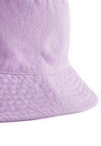 Chapeau seau lilas en tissu texturé, doté d'un large bord doux et de détails cousus le long du bord. Surface lisse.