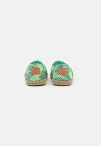 Espadrilhas verdes com padrão de folha de palmeira, sola de juta e um emblema em tom de caramelo no calcanhar. Projectadas com um bico redondo e plano, e tecido suave.