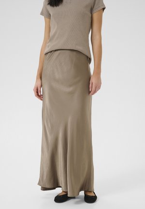 Gonna lunga e morbida di colore taupe neutro, realizzata in materiale leggero, abbinata a una maglietta ampia e testurizzata in tonalità coordinata.