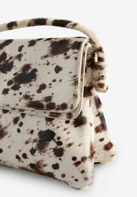 Hair-on leather handbag with a textured beige and brown spotted pattern, featuring a structured shape and a top handle.