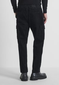 Schwarze Cordhosen im Cargo-Stil mit lässiger Passform, ausgestattet mit Seitentaschen und strukturiertem Stoff. Elastischer Bund für zusätzlichen Komfort.