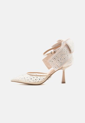 Beige puntige hoge hak schoen met enkelbandjes en doorzichtige meshpanelen versierd met kleine fonkelende strass-steentjes.