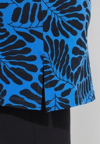 Tejido azul con un patrón de hojas negras, con una abertura lateral y detalles de costura visibles. Textura suave, diseño ajustado.