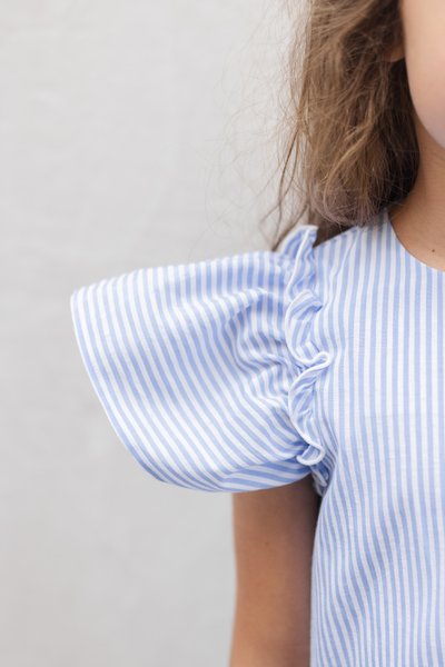 Φόρεμα σε γαλάζιες και λευκές ρίγες με puff μανίκια διακοσμημένα με βολάν. Λείο βαμβακερό ύφασμα με απαλή υφή και στρογγυλή λαιμόκοψη.