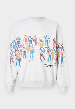 Felpa grigia con un'illustrazione colorata di sci sulla parte frontale, che mostra vari sciatori rappresentati in abbigliamento vivace e il testo "The Mountains" sotto.