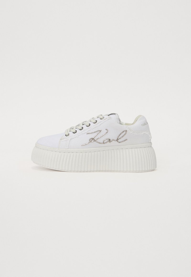 Sneakers bianchi in tela con suola piatta a righe, caratterizzati da ricamo argentato "Karl" sul lato e chiusura con lacci.