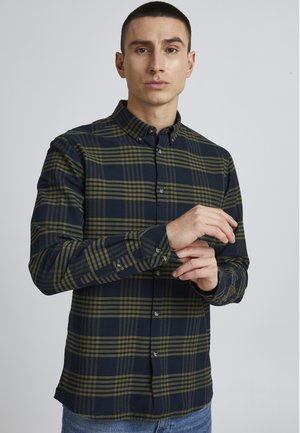 Men's long-sleeve shirt in navy and olive green plaid, cotton material, button-down collar, and visible button closures with contrasting buttons.