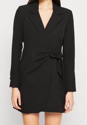 Robe noire à nouer en tissu lisse, dotée de manches longues, d'un décolleté en V profond et d'un détail noué à la taille, offrant une coupe cintrée.