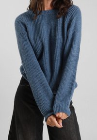 Maglione azzurro a coste realizzato in morbido tessuto a maglia, con maniche lunghe e vestibilità comoda, abbinato a pantaloni neri. Design accogliente e texture interessante.