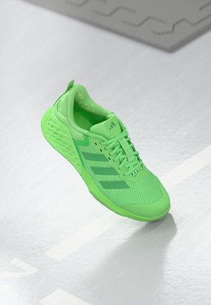 Chaussure de sport verte avec dessus en mesh, détails texturés et trois bandes vertes plus foncées. Dispose d'une semelle épaisse et rembourrée pour un bon soutien.