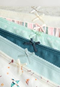 Syv par damestrusser i pastel farver og mønstre, hver med en lille dekorativ sløjfe på linningen.