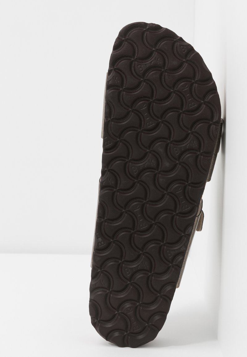 Braune Gummisohle mit einem strukturierten, wellenförmigen Grip. Die Seitenansicht zeigt ein minimalistisches Design mit schlanker Kontur und ohne sichtbare Merkmale.
