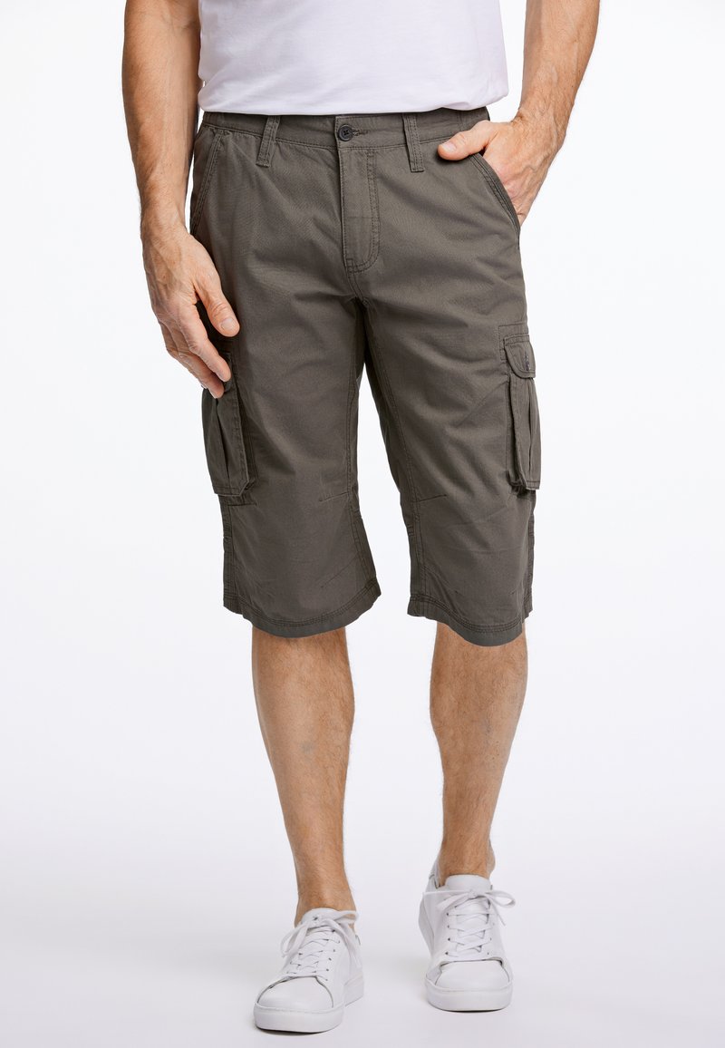 Olijfgroene cargoshorts, gemaakt van duurzaam materiaal, hebben zij- en achterzakken, een ontspannen pasvorm en stikseldetails. Gecombineerd met witte sneakers.