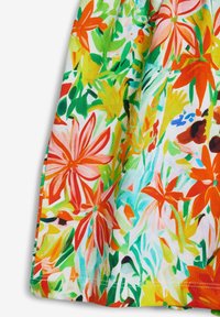 Blommig bomullstyg med livliga färger: orange, rosa, grön och gul. Designen inkluderar stora, djärva blomsterskulpturer och bladiga detaljer.
