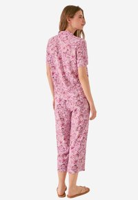 Roze bloemenpatroon pyjama set met een T-shirt met korte mouwen en cropped broeken, gemaakt van zachte stof met een relaxte pasvorm en subtiele glans.