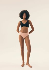 Czarny biustonosz typu bralette z okrągłym dekoltem oraz jasnoróżowe majtki z wysokim stanem. Materiał jest gładki o miękkiej fakturze, dopasowany do ciała.