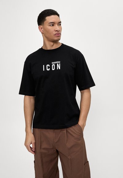 T-shirt en coton noir avec une coupe décontractée, arborant un bold logo blanc "ICON" et le branding "DSQUARED2" sur le haut de la poitrine. Manches courtes.