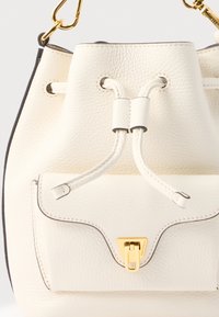 Borsa a secchiello in pelle bianca testurizzata con chiusura a coulisse. Presenta una tasca frontale con fermaglio color oro e bordi a contrasto.