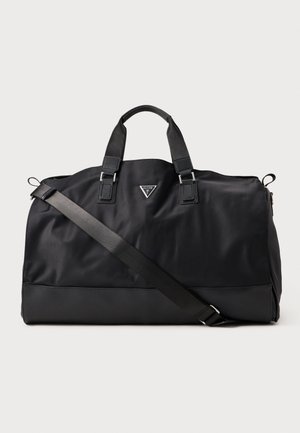 Sac de sport noir en nylon lisse avec des poignées doubles et une bandoulière amovible. Présente un logo triangulaire sur le devant.