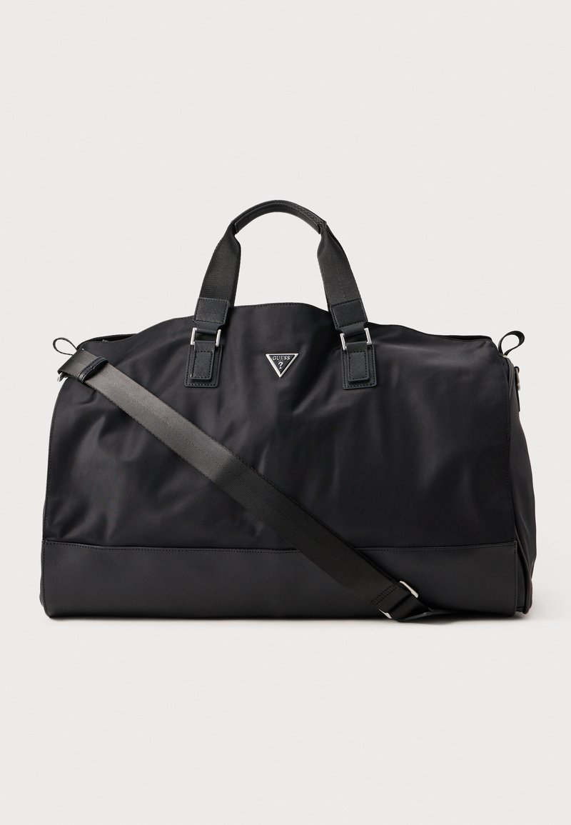 Sac de sport noir en nylon lisse avec des poignées doubles et une bandoulière amovible. Présente un logo triangulaire sur le devant.