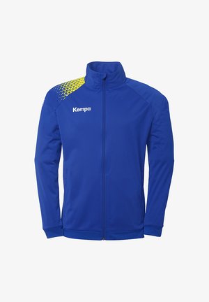 Blå sportsjakke lavet af glat stof med høj krave. Har et gult geometrisk mønster på skulderen og "Kempa" logo på brystet.