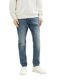 Jeans en denim bleu clair avec une coupe décontractée, un léger délavage, un design à cinq poches et une jambe droite. Assorties avec des baskets blanches.
