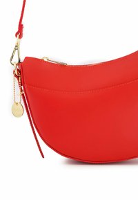 Red leather handbag with a curved design, gold hardware, and a detachable strap. Features a small pendant with "VENEZIA" engraved.
