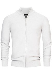 Cardigan blanc en tricot à fermeture éclair complète, avec col, poignets et ourlet côtelés, présenté de face sur un fond uni.