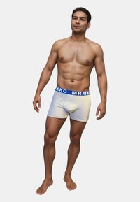 Grå boxershorts med ett blått elastiskt midjeband märkt "MR UKKO." Tyget har en slät textur och en figurnära design.