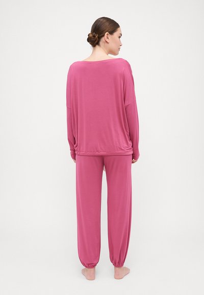 Ροζ σετ lounge που περιλαμβάνει ένα χαλαρό τοπ με μακρύ μανίκι και πτώση στους ώμους, καθώς και παντελόνια με ελαστικές μανσέτες για άνετη εφαρμογή.