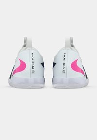 Λευκά αθλητικά παπούτσια με ροζ και μαύρες λεπτομέρειες, καμπύλη σχεδίαση, υφασμάτινη επιφάνεια και με λουράκι στο τακούνι. Λογότυπο αποτυπωμένο στο πλάι.