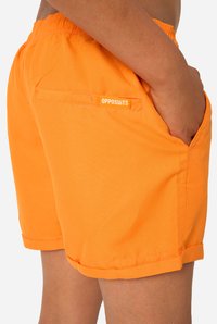 Oranje korte broek gemaakt van lichtgewicht stof met een elastische tailleband, zijzakken en een achterzak met het "OPPOSUITS" logo.