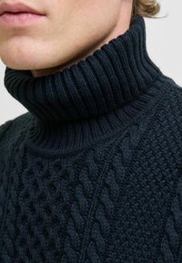 Pull en maille bleu marine avec col roulé et motifs en relief, présentant un fil épais pour la chaleur et le confort.