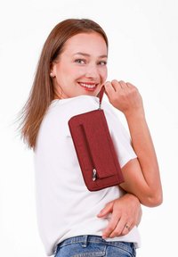 Red fabric wallet with a textured surface, featuring a zipper closure and a detachable wrist strap, held against a white background.