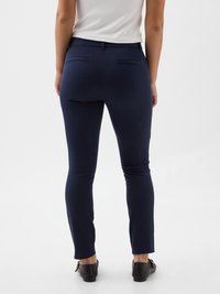 Navy blue fitted pants made of stretch material with a smooth texture. Features two back pockets and a mid-rise waist design.