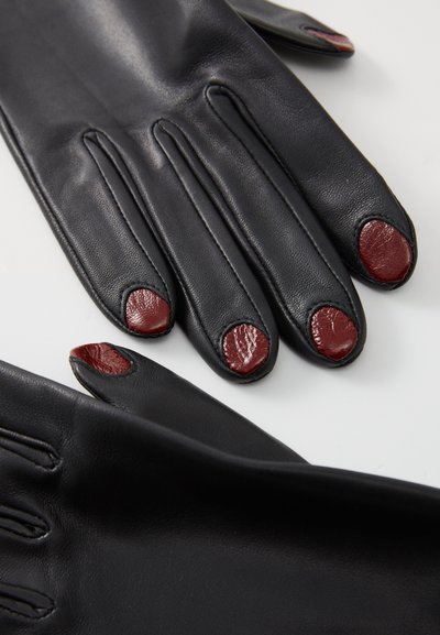 Gants en cuir noir avec cinq doigts, rehaussés d'accents en cuir rouge sur les extrémités des doigts. Texture lisse et design sur mesure.