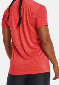 Red athletic short-sleeve shirt with a textured fabric. Features a classic crew neckline and a fitted design, suitable for active wear.