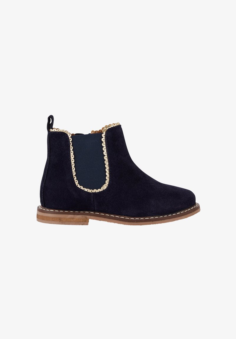 Bottines Chelsea en daim navy avec panneaux latéraux élastiques, garniture dorée, bout rond et talon bas empilé. Détails cousus autour de la semelle.